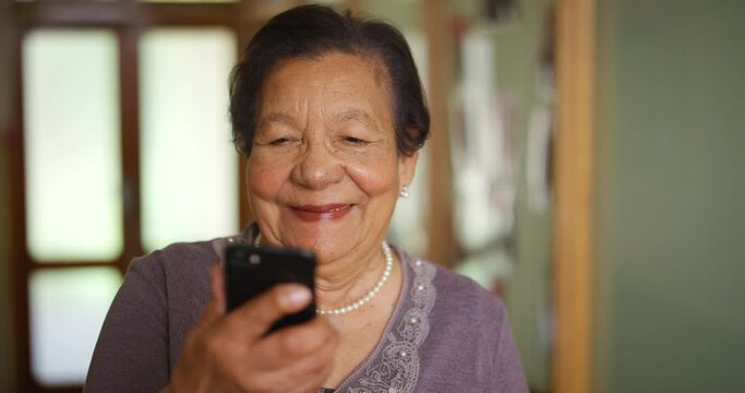 Senior, smile and phone of an elderly woman from China reading a text on a mobile at home. Happy Asian female using technology looking at web, internet or a online social media content with a smile