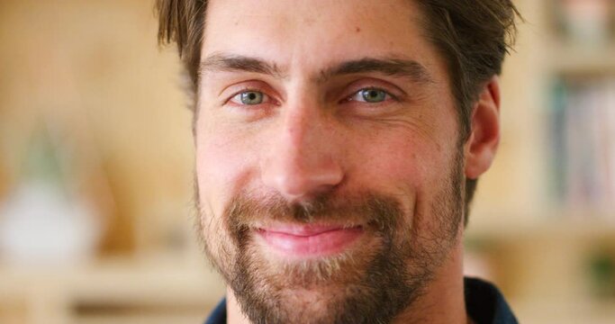 Portrait, face and smile of a handsome man for happiness, hope and positivity standing in a room. Closeup of a friendly, young and happy guy in an indoor creative space with a positive lifestyle.