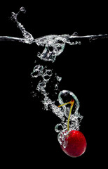Cherries splash in water on black background for fresh drinks advertising.