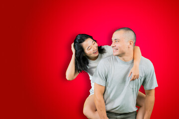 Happy man piggybacking his wife on studio