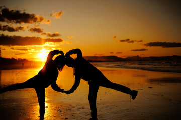 夕暮れ、全身でハートを作る男女のシルエット