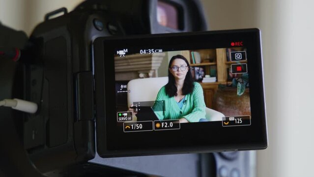 Close-up of caucasian, brunette woman in glasses within charming interior. Video recording of a lady in smart outfit as seen through camera screen. High quality 4k footage
