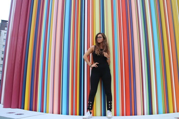 Model wearing black outfit with colorful background. Beautiful ginger hair girl posing for a fashion photoshoot.