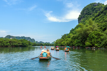 Fototapeta na wymiar Rowing boats carrying tourists on the river in Trang An, Ninh Binh province, Vietnam. Trang An is a world cultural and natural heritage recognized by UNESCO
