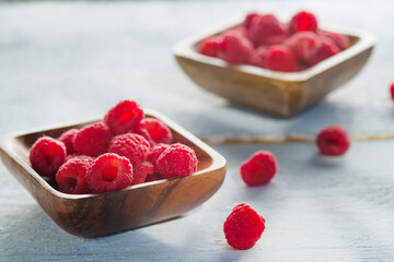 Two wooden bowls with juicy ripe raspberries on a white background. Delicious healthy product. Vitamins, antioxidants, healthy lifestyle, diet food.
