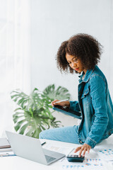 Young pretty african american freelancer working at office workplace, using computer tablet pc.