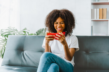 Excited cheerful gen Z female using mobile phone getting surprising good news while playing mobile...