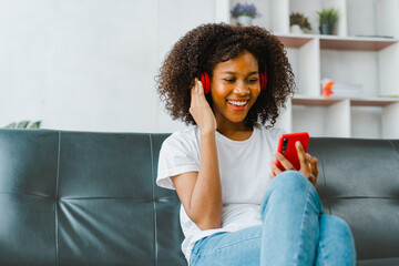 Young pretty african american woman happy with good music online on sofa at home.
