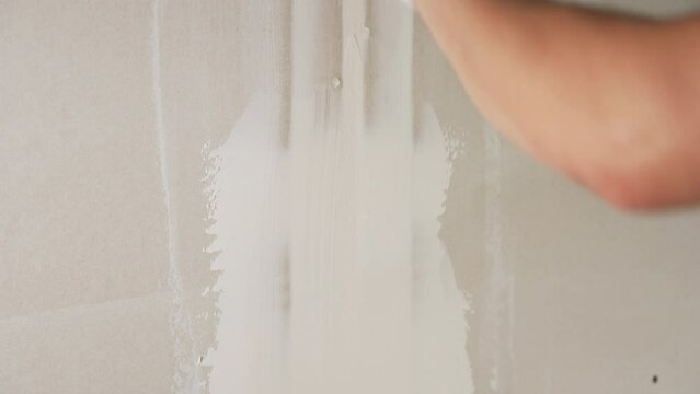 The builder puts plasterboard on the wall