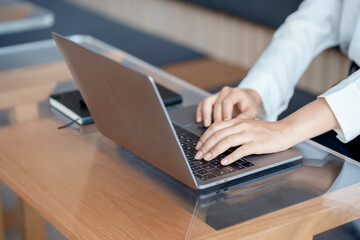 Close-up of hand of businesswoman working together using laptop computer to record and print information for a marketing plan analyze the balance sheet report quarterly financial statement.