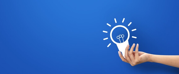 Hand holding bulb shape icon on blue background.