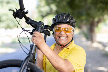 Obraz na płótnie Canvas Old man in helmet carrying mountain bike