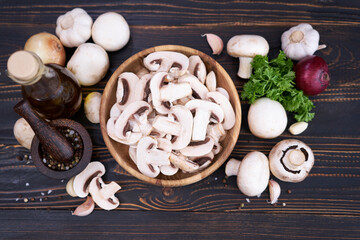 sliced raw champignon mushrooms in wooden bowl on the table
