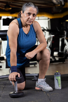 Woman Kneeling On Floor With Dumbbell
