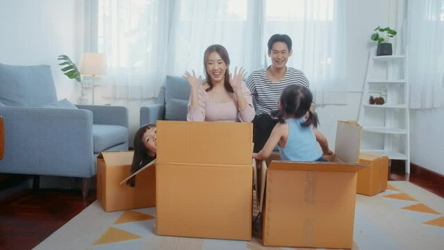 Asian family husband and wife and children with cardboard boxes having fun on moving day, Mortgage, loan, property and insurance concept.