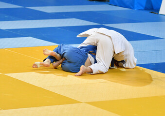 Fighter girls judoists in kimonos compete on the tatami 
