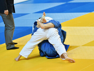 Fighter girls judoists in kimonos compete on the tatami 
