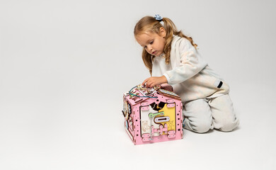 A little girl plays with an educational toy in the form of a house. Banner on the theme of childhood and development. Horizontal orientation, copy space