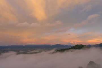 aerial view multicolored sky above the sea of mist..A sea of mist envelops the mountain peaks against the brightly colored sky at sunset..A sea of mist covers the mountain peaks