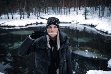 Girl with a knife in the winter near the lake in the forest.
