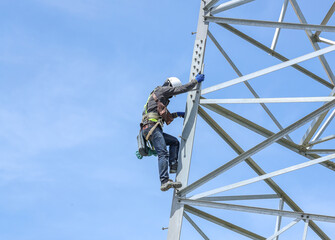 Worker climbing on transmission line steel tower