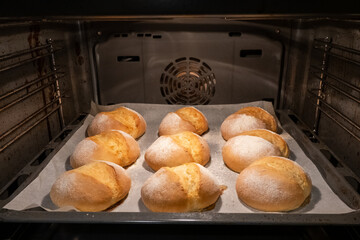 freshly baked crispy buns in the oven on the tray, process of cooking mini small bread from dough,...