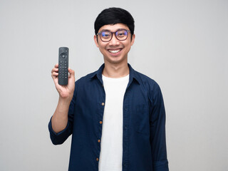 Asian positive man wear glasses smile show remote in his hand isolated