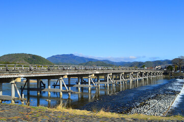 Fototapeta na wymiar 春に歩く京都市嵐山中之島から望む渡月橋と愛宕山