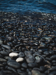 Close up view of Koh Hin Ngam Island iconic black round pebble stone beach. Near Koh Lipe Island, Tarutao National Marine Park, Satun, Thailand. Selective focus, blurred foreground and background.