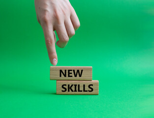 New skills symbol. Wooden blocks with words New skills. Beautiful green background. Businessman hand. Business and New skills concept. Copy space.