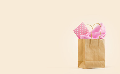 Gift or Sale concept. Shopping buff paper bag, with pink tissue. Polka dot gift card. Copy space. Holiday birthday. Packaging. Cosmetics or girls stuff order delivery. baby shower for girl