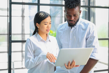 Modern business people are working using laptop and smiling while standing in the office.