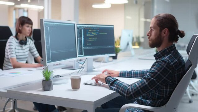 Close up of young handsome male IT specialist coding program typing on computer looking at screens while sitting in office. Male data scientist working in company programing. Big data, IT Technician