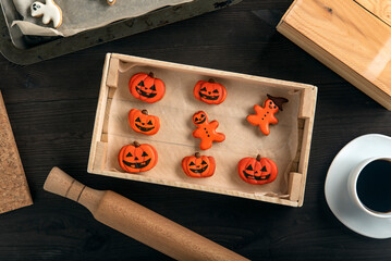 Fototapeta na wymiar Ginger cookies in pumpkin shape for Halloween lie in a wooden tray on the table. Very tasty to eat with a cup of coffee