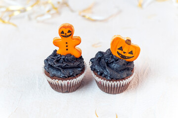 Festive Halloween cupcakes decorated with gingerbread cookies. Homemade sweets for the celebration of Halloween. Yellow