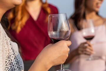 Photo of close up of the wineglass of a group of female friends cheering each other and enjoying their time in a rooftop bar in Bangkok during sunset time