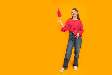 Girl holds the flag of Turkey. Full-length portrait of teenager on yellow background. Learning Turkish. Work in Turkey for young people.