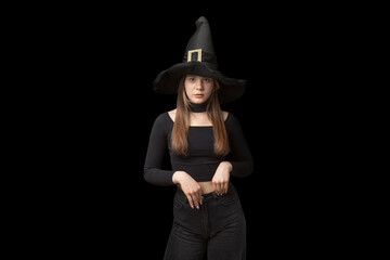 Portrait of teenager in pointed witch hat and black clothes is isolated on black background....