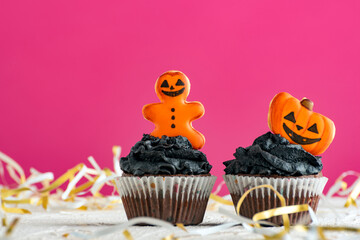 Two cupcakes for the celebration of Halloween on pink background. Halloween cupcake with pumpkins...