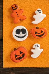 Halloween Ginger cookies in the form of a pumpkin and ghosts on orange background. Smiling cookie. Top view.