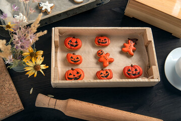 Orange gingerbread in pumpkin shape for Halloween lie in a wooden tray. Tasty cookie on table