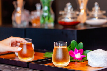 Woman hand take a herbal spa tea in a glass cup