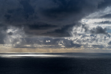 Obraz premium sun breaking through dark clouds over the Atlantic Ocean seen from the Irish coast in spring at the cliffs of moher
