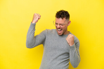 Young caucasian handsome man isolated on yellow background celebrating a victory