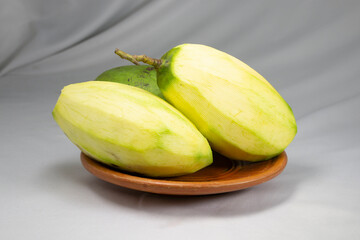 peeled green mango on clay plate.