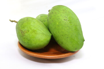 unpeeled green mangoes on clay plate. studio photo shoot.