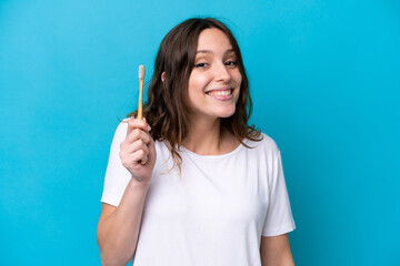 Young caucasian woman brushing teeth isolated on blue background with surprise and shocked facial expression