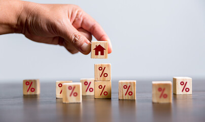 Hand building a house by wooden cubes with the percentage sign on them. Concept of Interest rate...