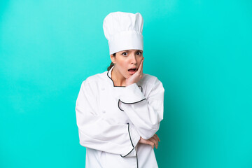 Young caucasian chef woman isolated on blue background surprised and shocked while looking right