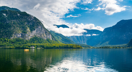 Fototapeta na wymiar Hallstatt see lake near the Salzburg city. View of lake and big mountains in background. Cloudy weather, big clouds and mist over lake.